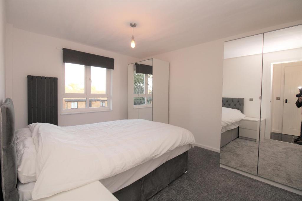 a white bedroom with a large bed and a mirror at Lovely Flat Near Lewisham in Hither Green