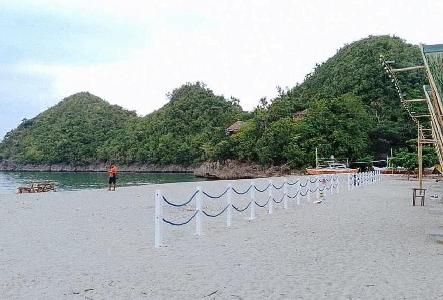 a beach with a row of flags on the sand at Langub Beach Resort Sipalay by RedDoorz in Sipalay