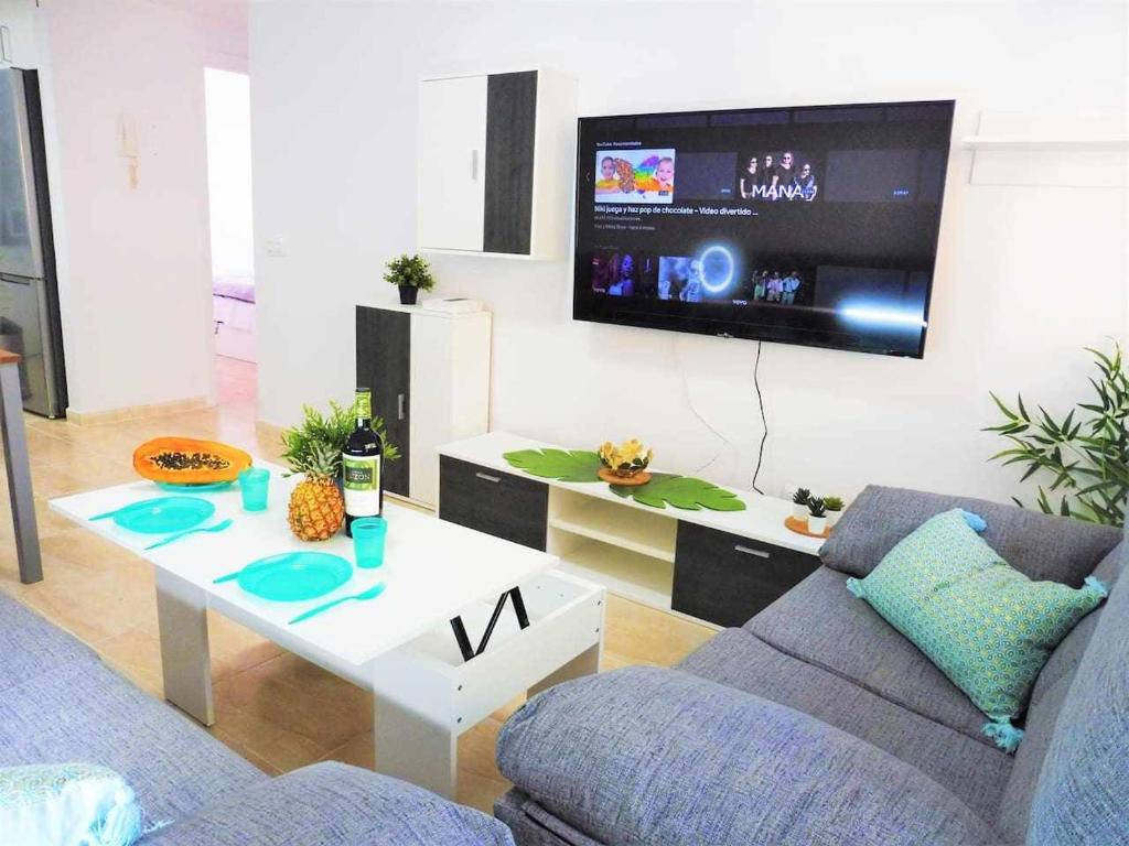 sala de estar con sofá, mesa y TV en Vacaciones Sur Tenerife Ofogar, en San Isidro