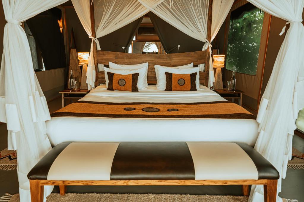 a bedroom with a large bed with a canopy at Soroi Luxury Migration Camp in Sekenani