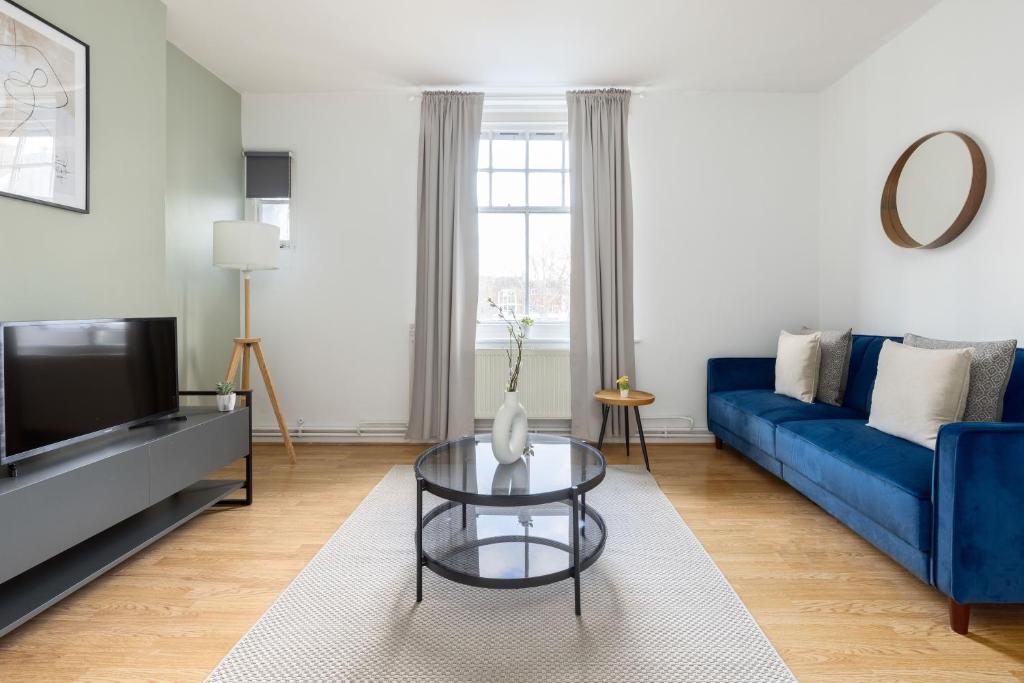 a living room with a blue couch and a glass table at The Shoreditch Collection in London