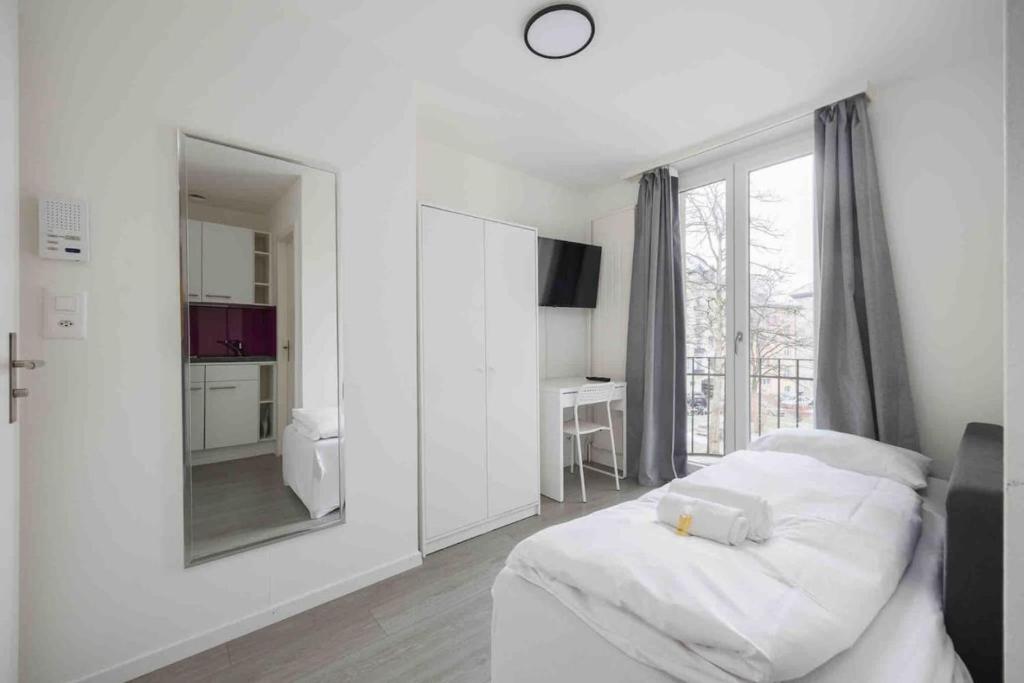 a white room with a bed and a mirror at Cozy Urban Studio in the City BE-21 in Zurich