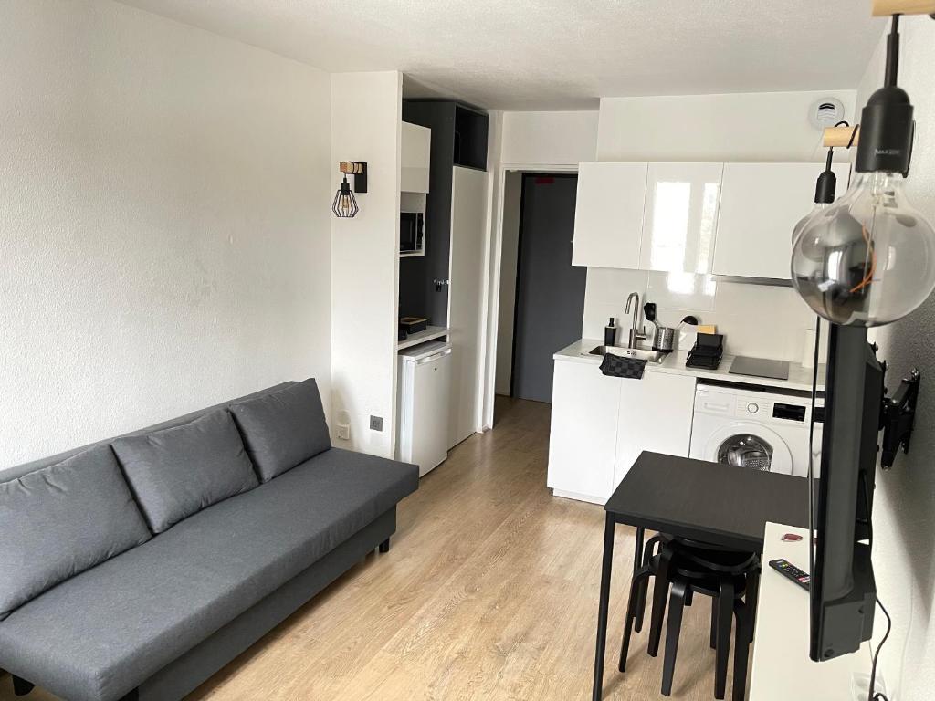 a living room with a couch and a table and a kitchen at T2D Apartment - Suite UR proche Disneyland Paris in Bussy-Saint-Georges