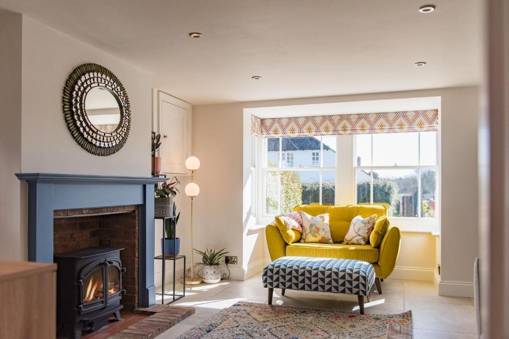 uma sala de estar com um sofá amarelo e uma lareira em Wheelwrights Cottage by Bloom Stays em Staple Cross