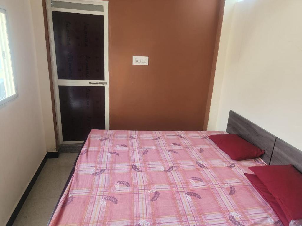 Kailash kuti Guest House في اوجاين: غرفة نوم مع سرير مع لحاف وردي