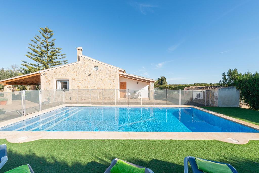 a swimming pool with chairs in front of a house at Son March I in Sa Pobla