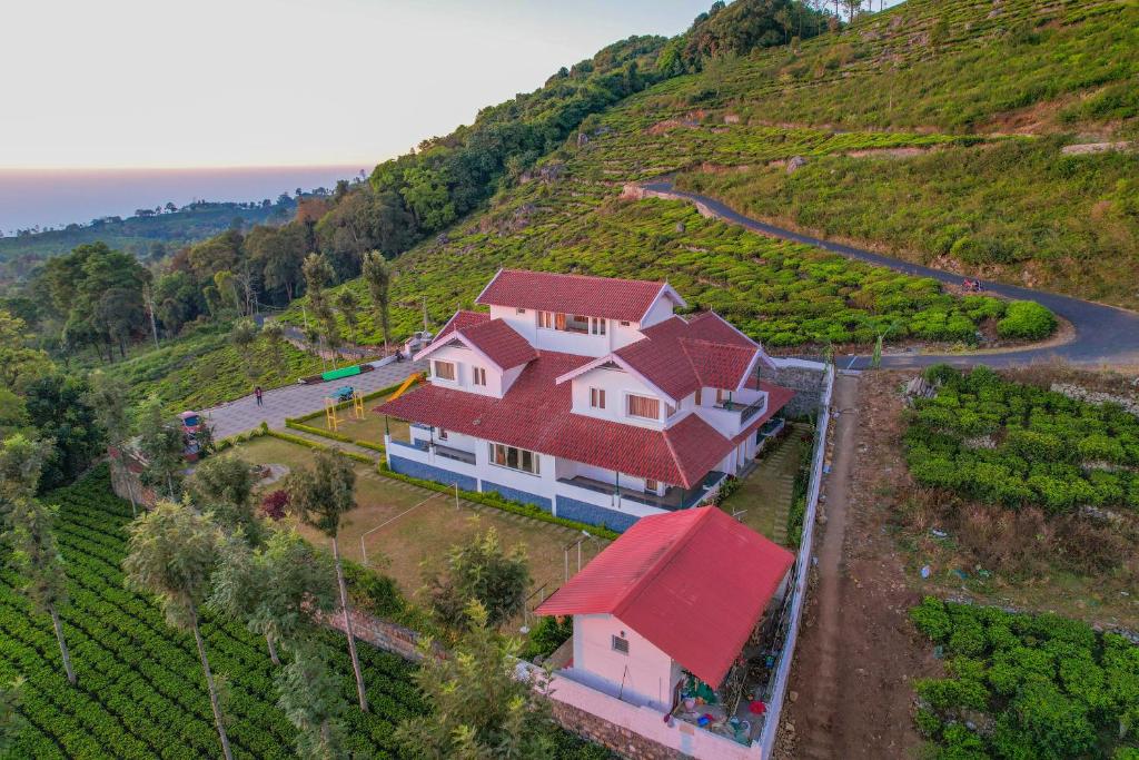 una casa con techo rojo en una colina en Mystique stay resort, en Kotagiri