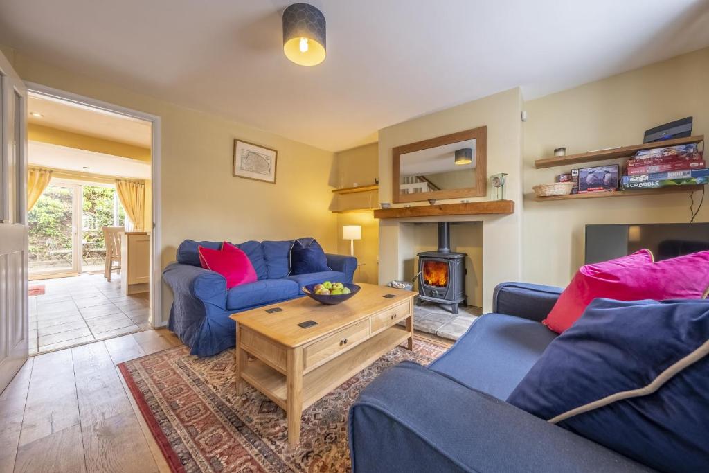 a living room with two blue couches and a fireplace at Poppy Cottage H in Holt