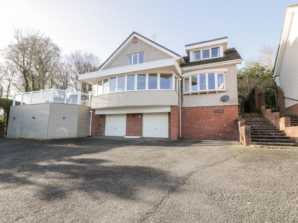 a large white house with a garage in a driveway at 11 Glyn Garth Mews in Llandegfan