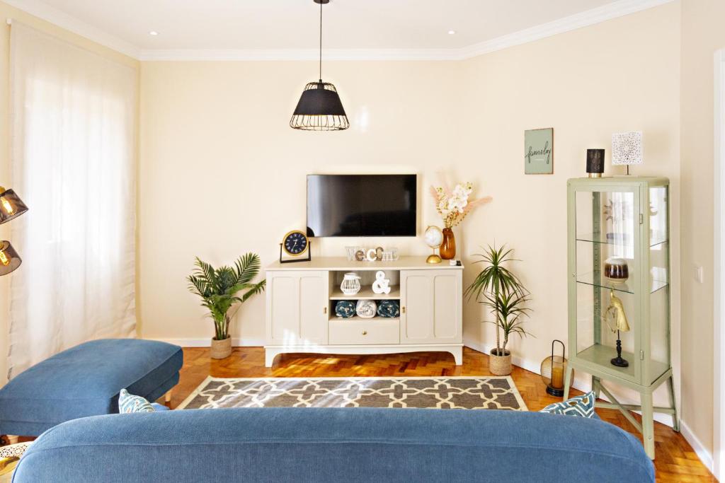 a living room with a blue couch and a tv at Blue Peacock in Faro