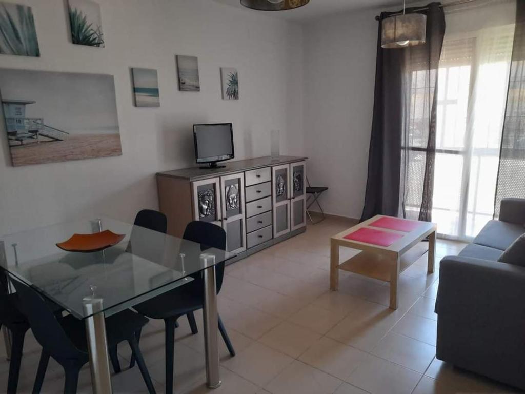 een woonkamer met een eettafel en een televisie bij Apto. Dunas Playa in Isla Cristina