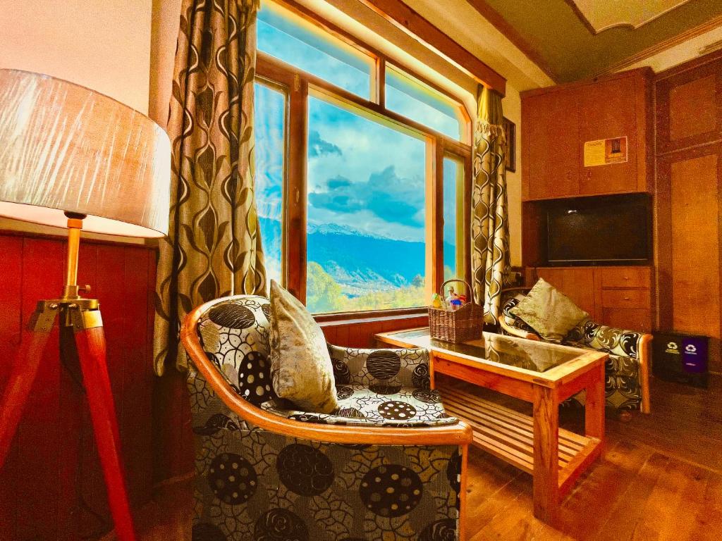a living room with a chair and a large window at Woods Villa Cottage, Manali in Manāli