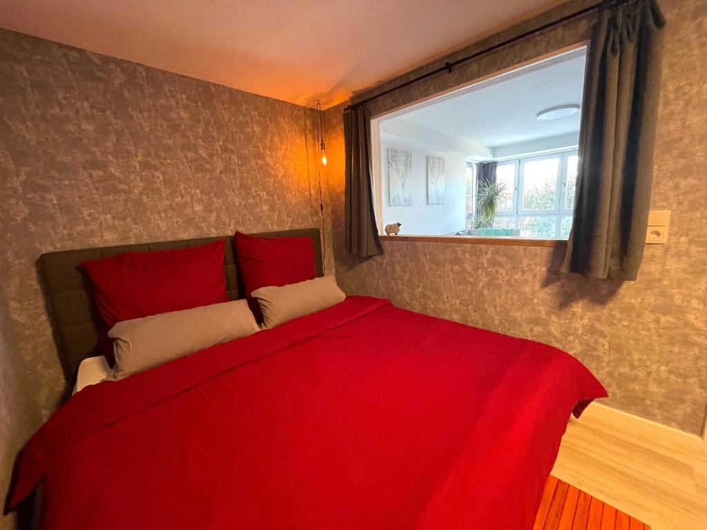 a bedroom with a red bed with a window at FeWo “ruhige Momente” in Waldkirch in Waldkirch