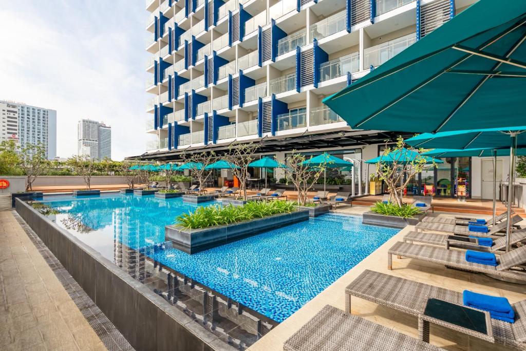 a swimming pool with blue umbrellas next to a building at TUI BLUE Nha Trang in Nha Trang