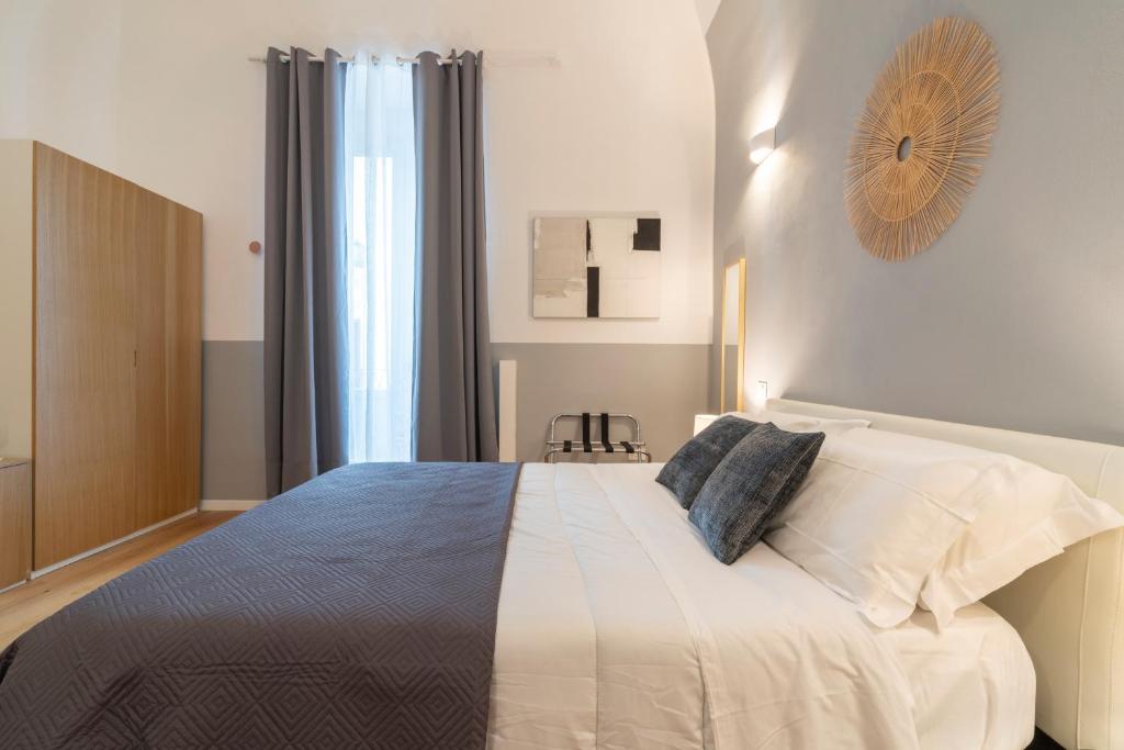 1 dormitorio con 1 cama grande con sábanas y almohadas blancas en SoClà Boutique Hotel, en Taranto