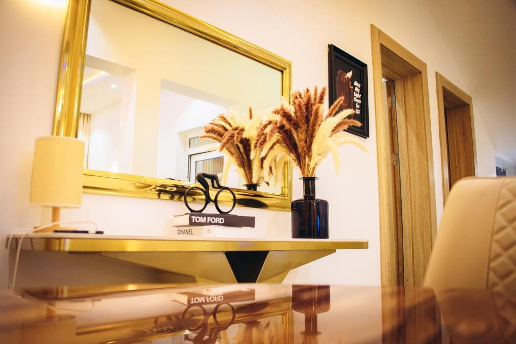 einen Schreibtisch mit Spiegel und eine Vase mit Brille in der Unterkunft D'Reserve Luxury Apartment Sagamu in Sagamu