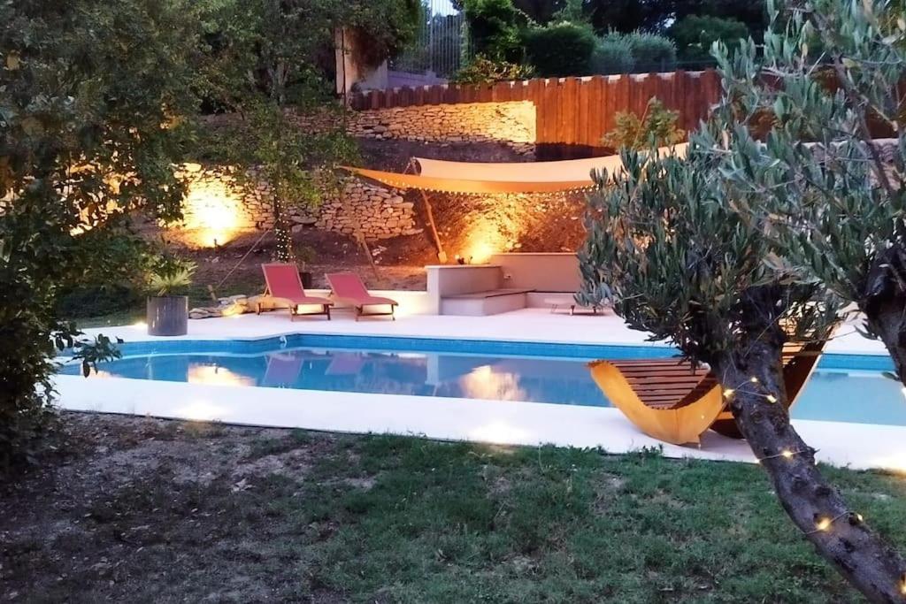 een zwembad in een achtertuin met stoelen en een tafel bij Un écrin à Cornillon en Provence in Cornillon-Confoux