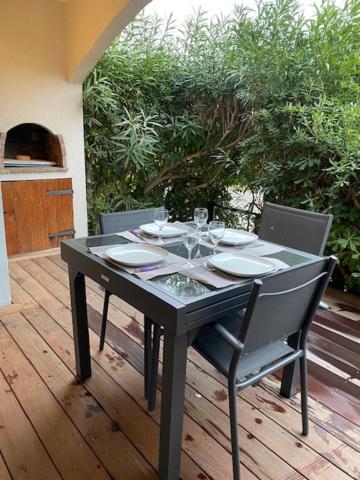a table with plates on it on a wooden deck at LE KALI in Cavalaire-sur-Mer