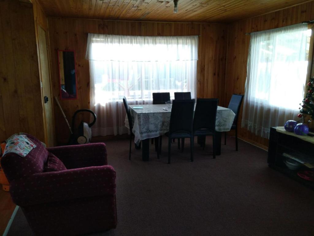 ein Esszimmer mit einem Tisch, Stühlen und einem Fenster in der Unterkunft Casa in Quellón