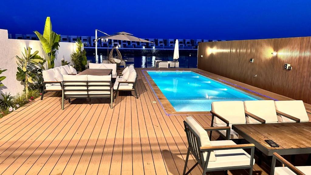 eine Terrasse mit Stühlen und ein Pool in der Nacht in der Unterkunft Luxury Villa 5 bedrooms with sea view and free boat in Fudschaira