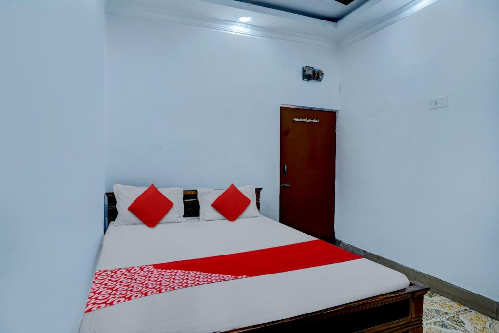 Schlafzimmer mit einem Bett mit roten und weißen Kissen in der Unterkunft Hotel Sourya Residency in Jamshedpur