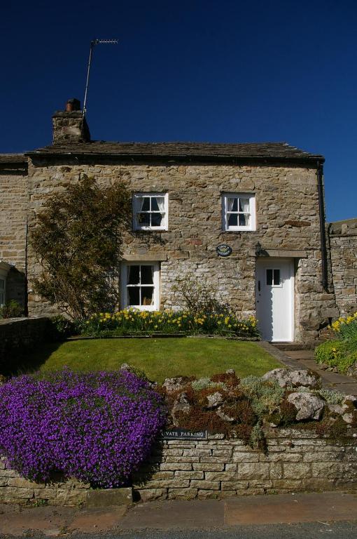 a stone house with purple flowers in front of it at Cissy's Cottage in Hawes
