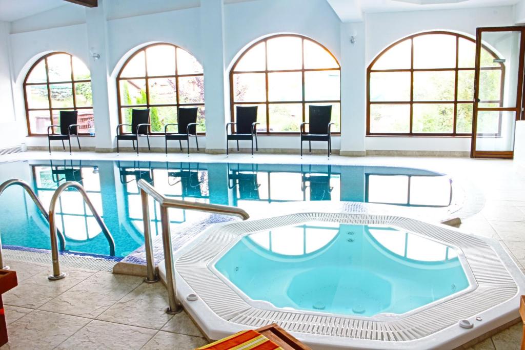 einen großen Pool mit Stühlen und Tischen in der Unterkunft Hotel Esprit in Braşov