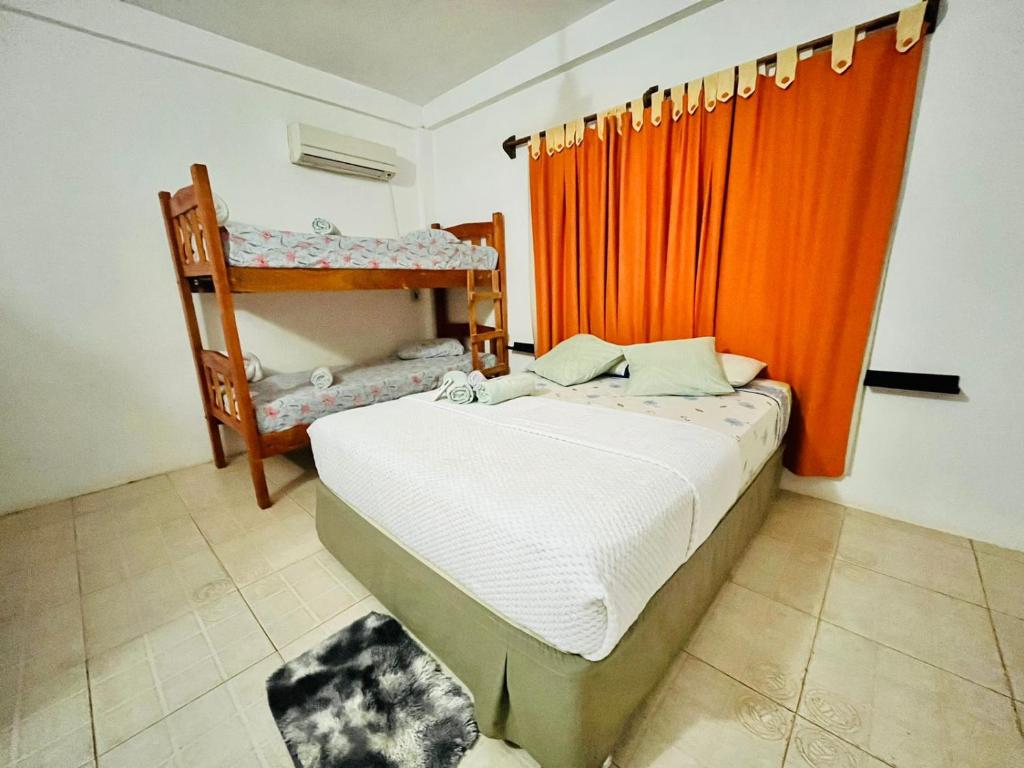 sypialnia z łóżkiem z pomarańczową zasłoną w obiekcie Hiraya Apart w mieście Puerto Iguazú