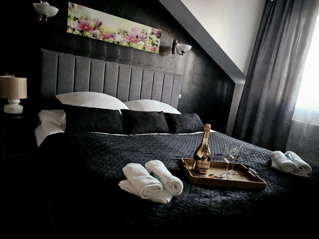 - une chambre avec un lit, des serviettes et une bouteille de champagne dans l'établissement Hotel Kasieńka, à Hrubieszów