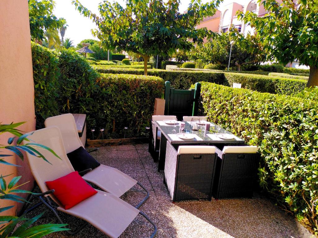 une terrasse avec une table, des chaises et des verres à vin dans l'établissement Nid douillet F2, clim, jardin, piscine, parking, plage 200 m Palavas, à Palavas-les-Flots