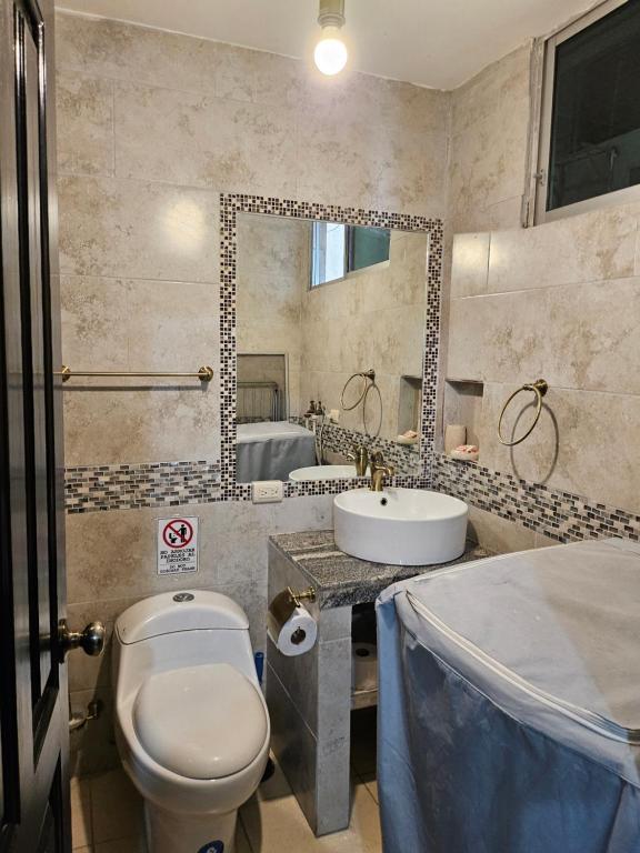 a bathroom with a toilet and a sink and a mirror at Blanca Apartments in Guayaquil