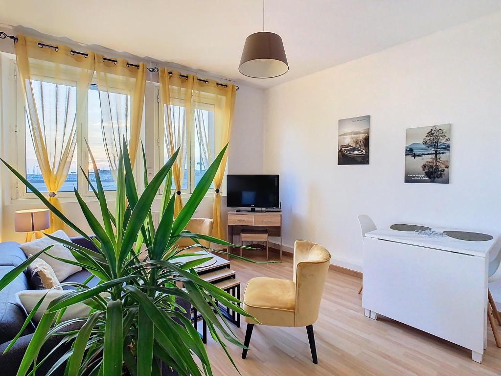 ein Wohnzimmer mit einer Pflanze, einer Couch und einem TV in der Unterkunft Horizons "Vue Mer" in Royan