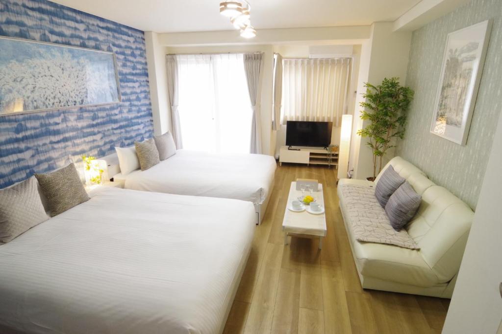 um quarto de hotel com duas camas e um sofá em Matsuyamachi Shimanouchi Building - Vacation STAY 14368 em Osaka