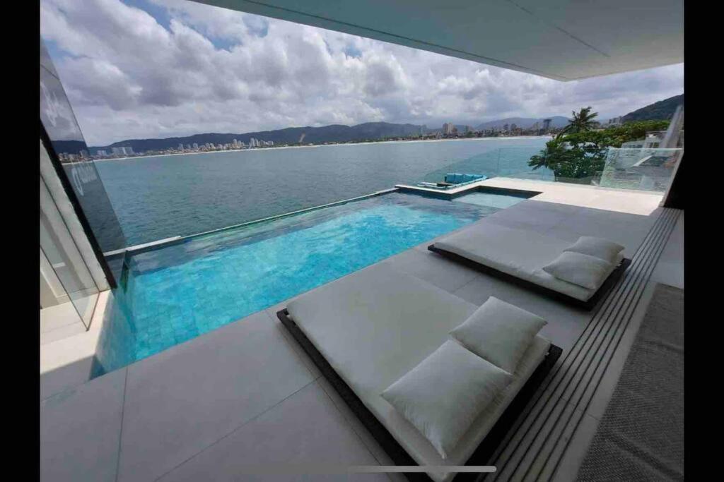 a swimming pool with a view of the water at Mansão com vista cinematográfica pro mar! in Guarujá