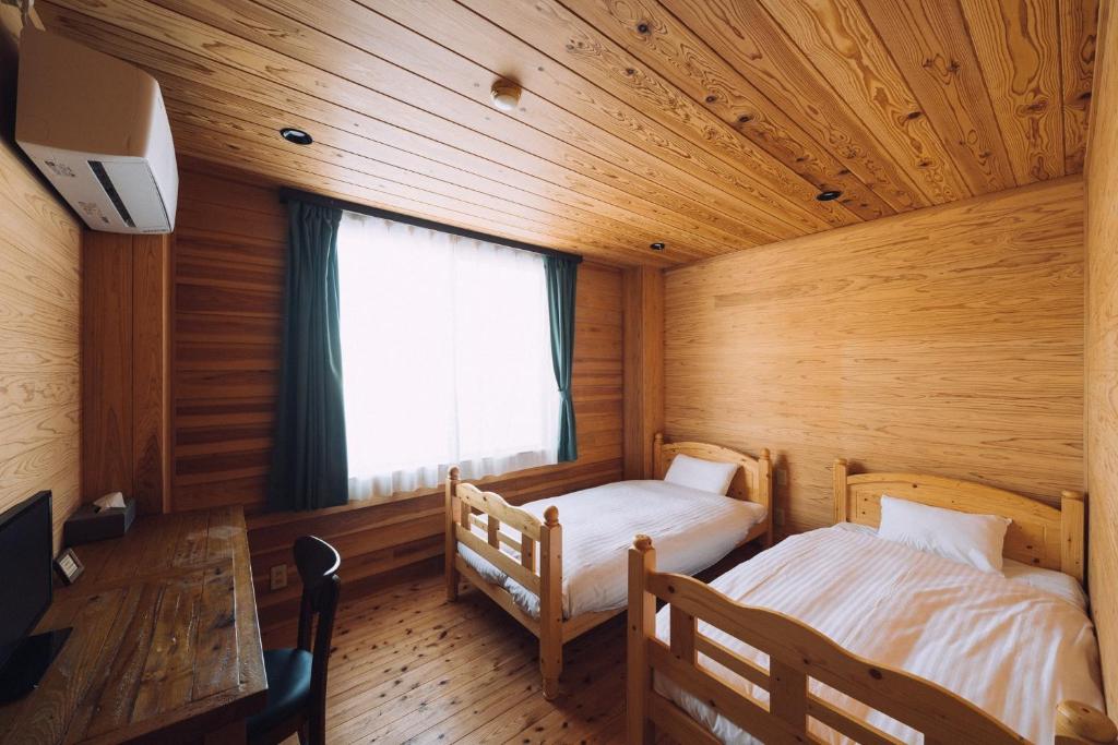 a bedroom with two beds in a wooden room at Noasobi lodge - Vacation STAY 80823v in Arao