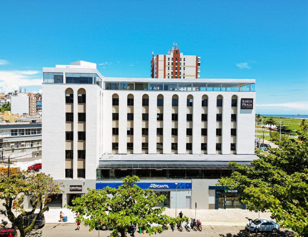 Un bâtiment blanc avec des gens qui marchent devant lui dans l'établissement Ilhéus Praia Hotel, à Ilhéus