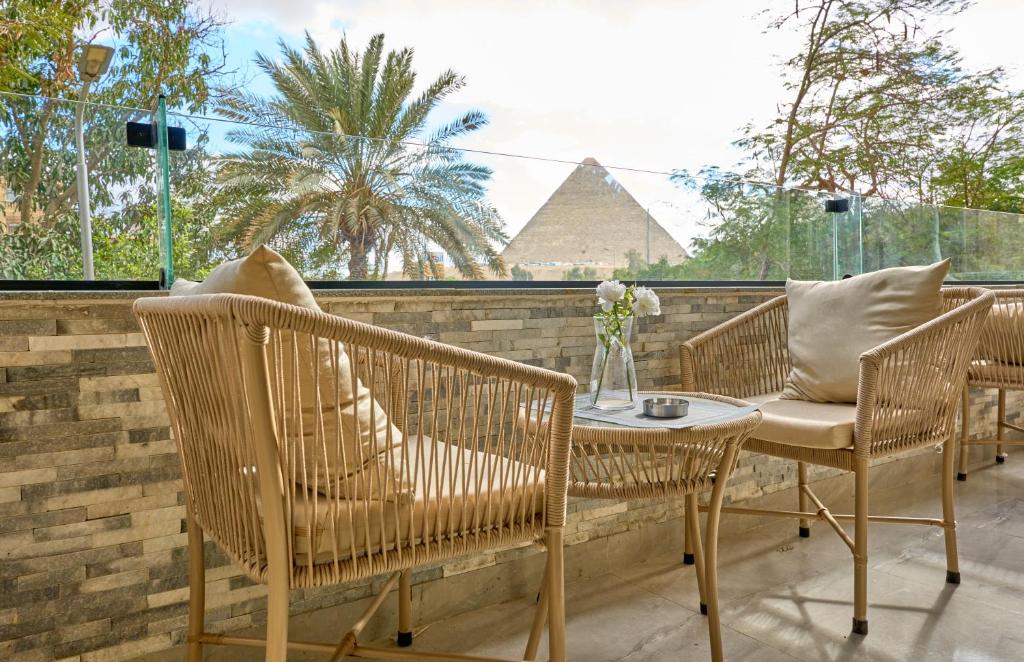 eine Terrasse mit Stühlen und einem Tisch mit einer Pyramide im Hintergrund in der Unterkunft Lotus Inn in Kairo