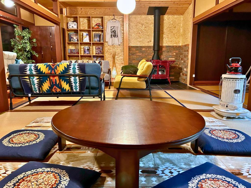 uma sala de estar com mesa e cadeiras em ゲストハウスでたらめ荘 em Yamakami