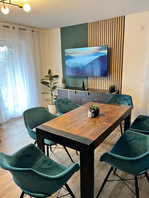 a dining room with a wooden table and green chairs at Auszeit am Berg in Lenzkirch