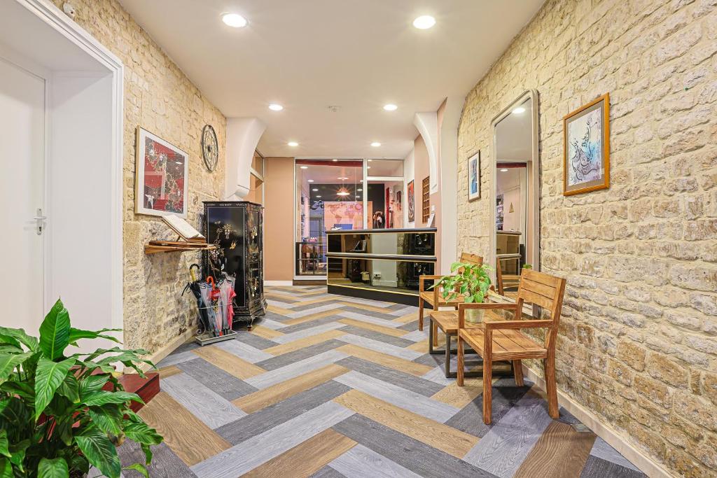 un couloir avec une table et des chaises ainsi qu'un mur en briques dans l'établissement Hôtel François d'O, à Caen