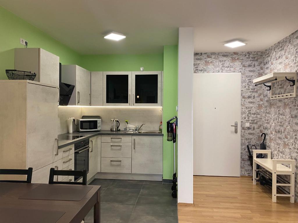 una cucina con armadi bianchi e pareti verdi di Schönes 2 Zimmer Apartment zentral gelegen a Pforzheim