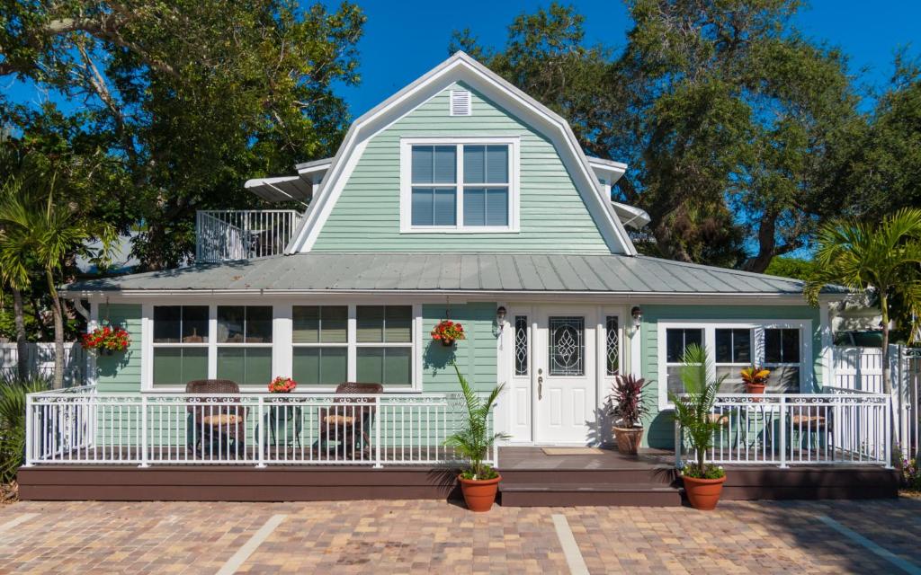 a green house with a white porch and chairs at SeaGlass Inn Bed and Breakfast in Melbourne Beach