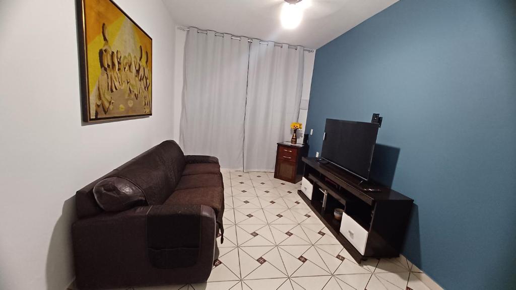 a living room with a couch and a flat screen tv at Balneário Jussara in Mongaguá