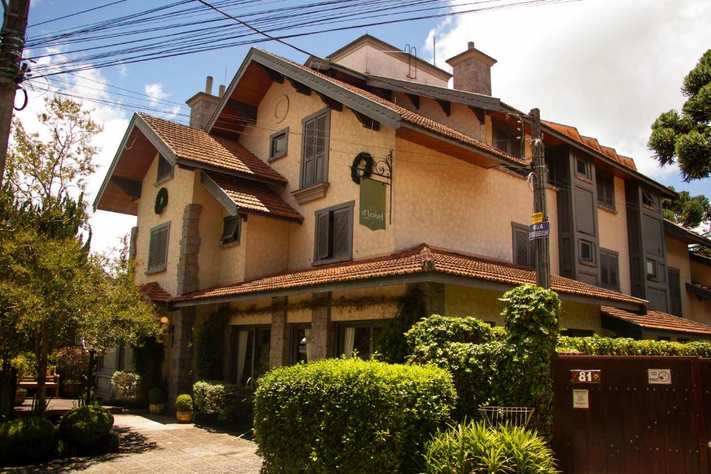 une grande maison avec des buissons devant elle dans l'établissement Hotel Solar d'Izabel, à Campos do Jordão