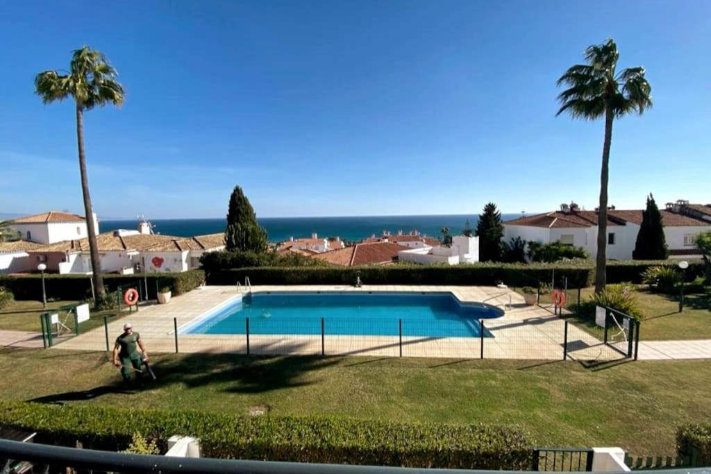 ein Swimmingpool mit Palmen und dem Meer in der Unterkunft Terrazas de Guadalupe - Sea view in Manilva