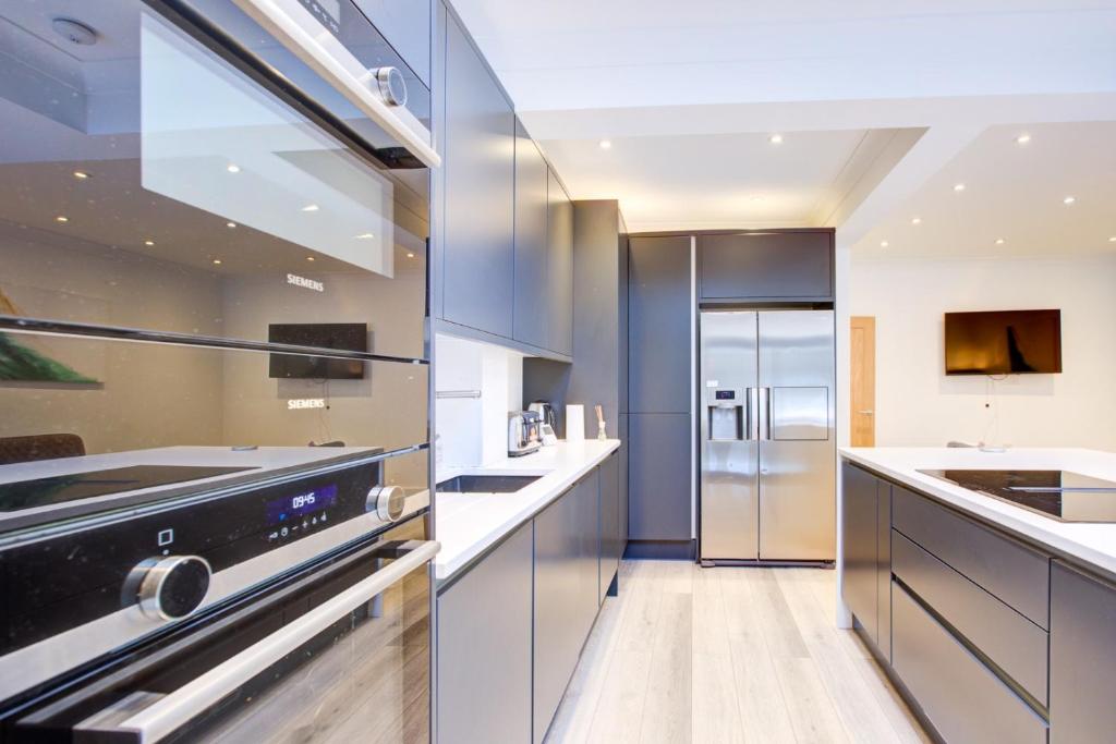 a large kitchen with a stainless steel refrigerator at Exquisite 5-Bedroom in London and Essex - Sleeps 10 with Free Parking in Romford