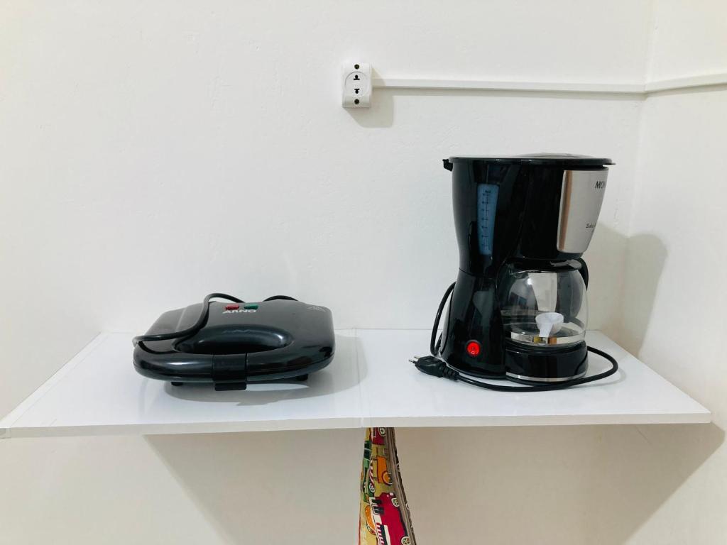 Sacavem Flat Hotel Navegantes في نافيغانتس: آلة صنع القهوة على رف مع وعاء القهوة