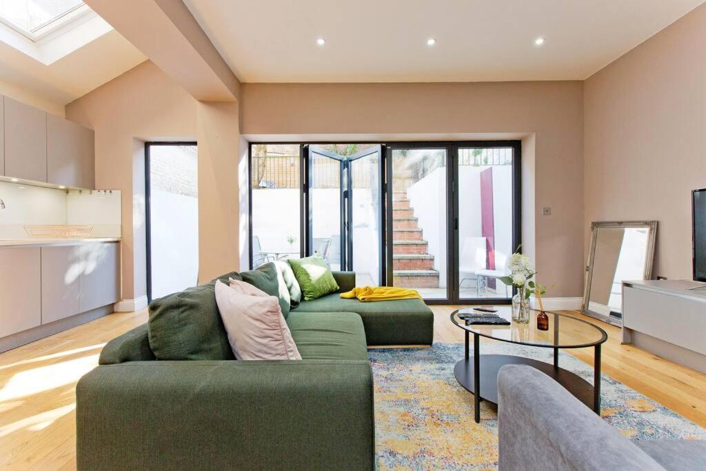 a living room with a green couch and a table at Spacious 3bed kensington in London