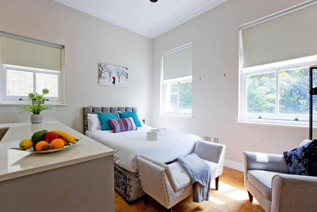 Un dormitorio con una cama y una mesa con un bol de fruta en Bright and cheerful studio, en Londres