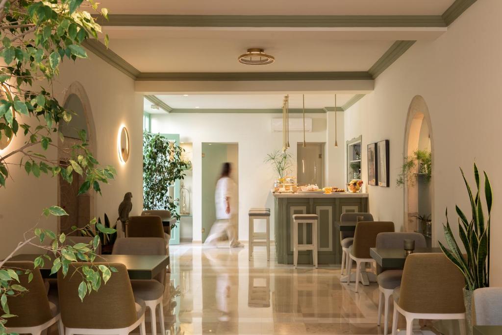 a room with chairs and tables and a person in the background at Mythos Suites Boutique Hotel in Rethymno